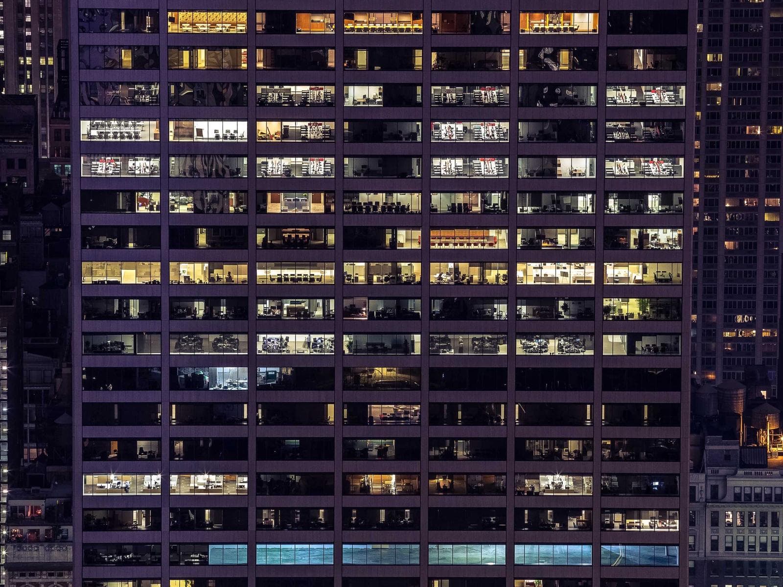 An apartment building at night with lights on in most windows